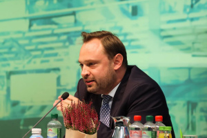 Alexander Dierks, Generalsekretär der CDU Sachsen spricht auf dem Podium. Vor ihm stehen Getränke und eine kleine Pflanze.