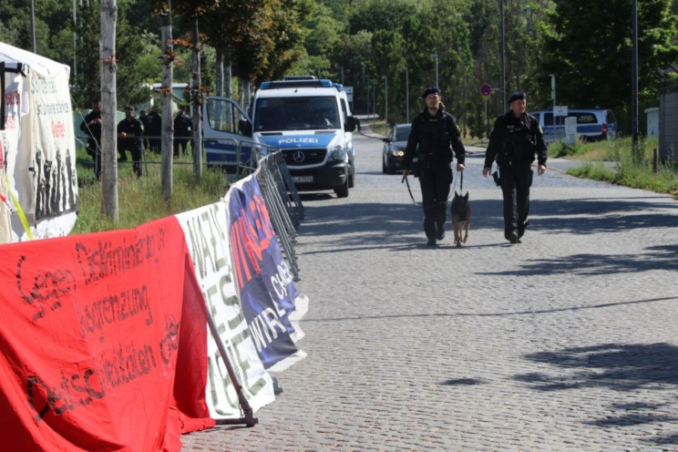 Transparente, Polizisten mit Hund auf abgesperrter Straße.