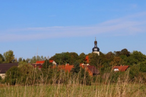 Pödelwitz, Häuser, Kirchturm und blauer Himmel.