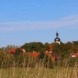 Pödelwitz, Häuser, Kirchturm und blauer Himmel.