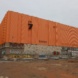 Katenförmiges Gebäude mit oranger Verkleidung von außen.