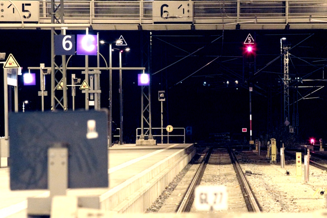 Bahnhofshalle von außen mit Schiene, leerem Bahnsteig und Signalen.