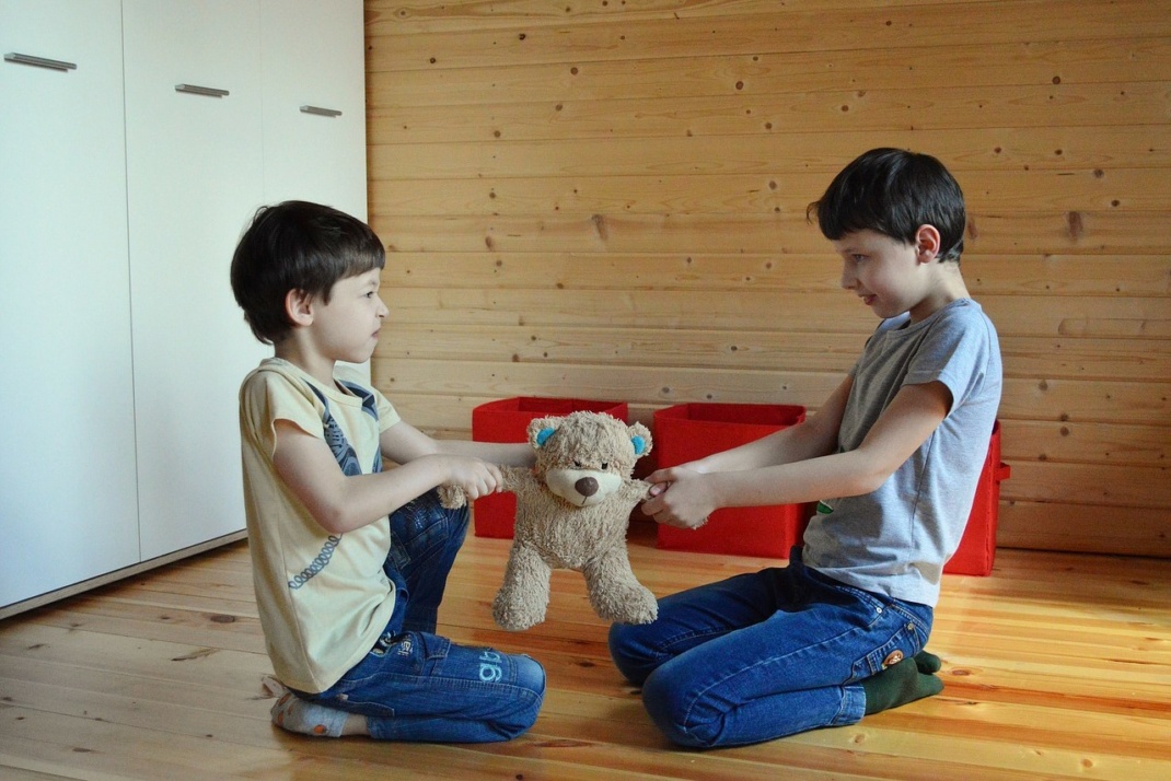 Zwei streitende Kinder mit einem Teddybären in der Mitte