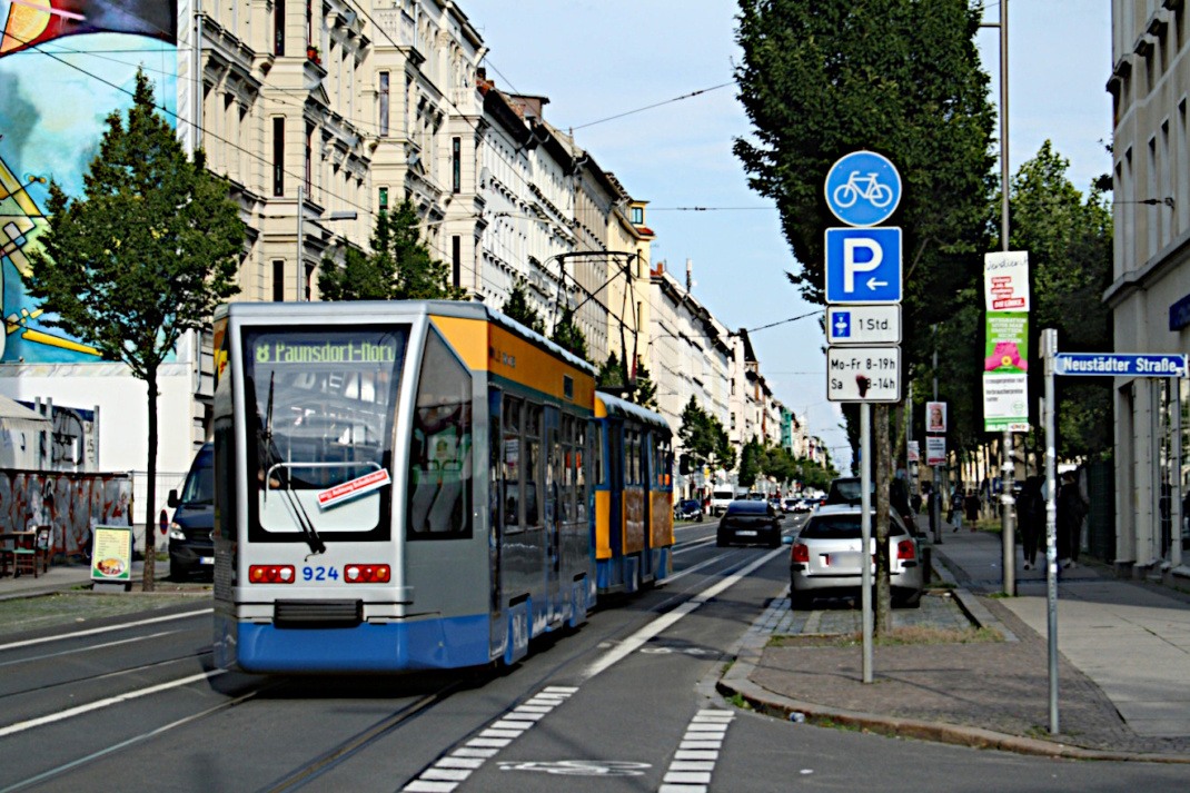 Belebte Hauptstraße, Straßenbahn und parkende PKW.