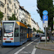 Belebte Hauptstraße, Straßenbahn und parkende PKW.