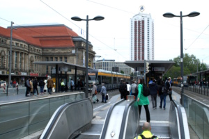 Haltestelle am Bahnhof, Straßenbahnen und viele Personen.