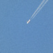 Flugzeug mit Kondensstreifen am blauen Himmel.