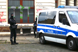 Vermummte Polizisten, Polizeiwagen.