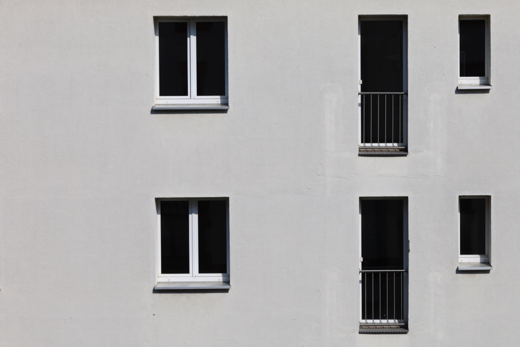 Helle Hausfassade mit Fenstern.