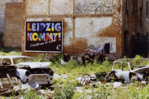 Straßenszene aus den Neunzigern, Müllhalde und Slogan an Mauer.