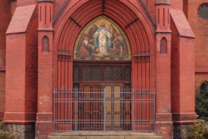 Rotfarbenes Kirchgebäude, Portal mit Christusdarstellung.
