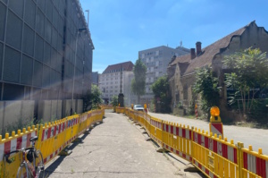 Provisorischer Weg mit Baustellenmarkierungen in der Stadt, blauer Himmel.