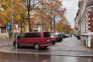 Gehweg an Straße, parkende Autos.