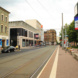 Städtischer Platz mit Wohnhäusern, Straßenbahnschienen und Autos.