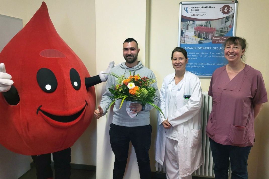 Maskottchen Blutbert, Dr. Lisa-Marie Dilz (2. v. r.) und Dr. Rebecca Großmann vom ITM bedankten sich bei Stammzellspender Niclas Wittmann mit einem großen Blumenstrauß für dessen Engagement. Foto: Janina Sommermeyer / UKL