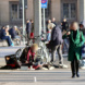 Obdachlose Personen auf Bahnhofsvorplatz, viele Menschen unterwegs,