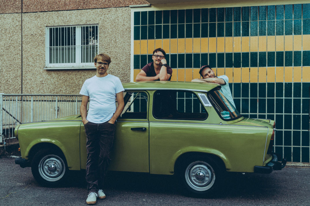 Drei Männer vor einem Trabant, im Hintergrund ein Wohnblock