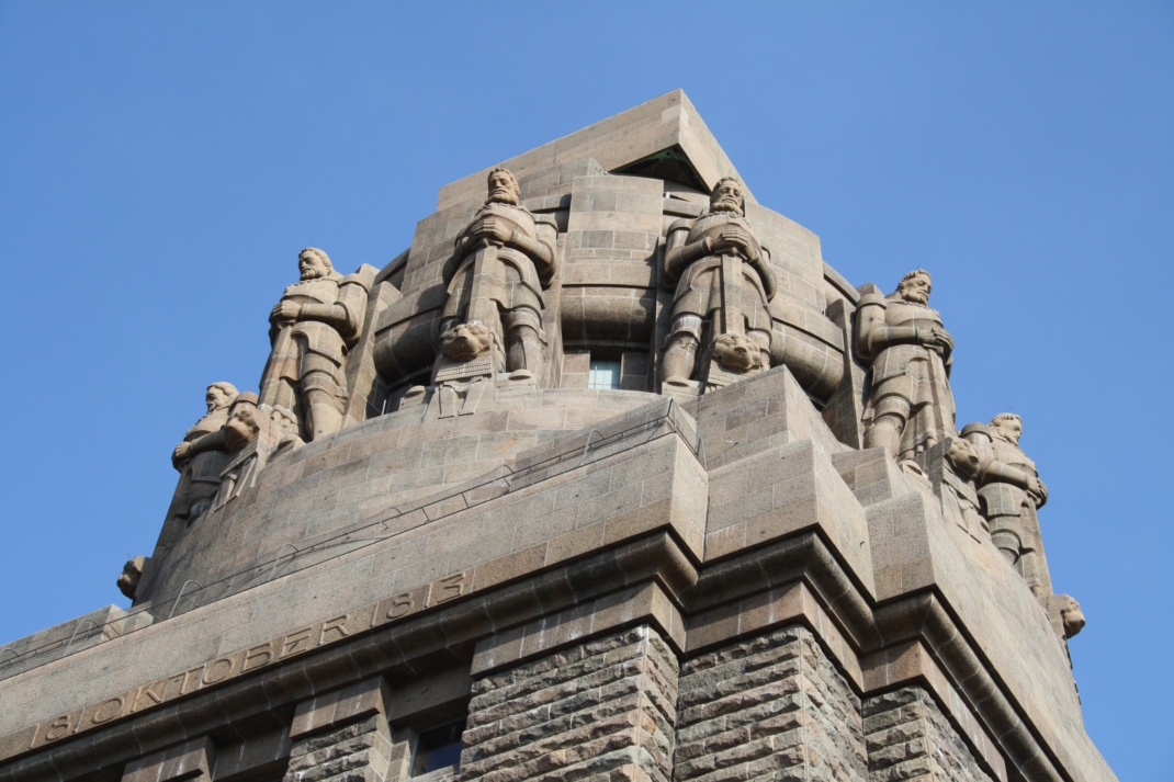 Völkerschlachtdenkmal, Aufnahme von schräg unten, mit Blick auf steinerne Wächterfiguren.