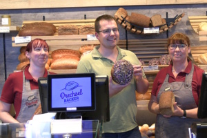 Ein Mann und zwei Frauen stehen am Tresen einer Bäckerei.