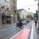 Städtische Haltestelle mit rot markiertem Radweg auf der Hauptstraße, Radlern und Autofahrern.