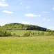 Sattelbergwiese im Osterzgebirge, grüne Wiese, Wolken und blauer Himmel.