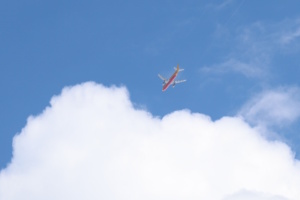 Flugezug am Himmel, aufgenommen vom Boden aus, Wolken und blauer Himmel.