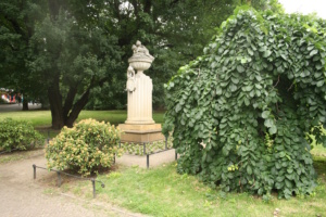 Zu sehen ist das Gellert-Denkmal in der Lennéanlage. Es ist von einer Umzäunung, Wiesen, Bäumen und Sträuchern umgeben.