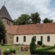 Helles Kirchengebäude mit Friedhof.