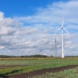 Windkraftanlage auf freiem Feld, blauer Himmel und Wolken.