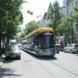 Hauptstraße, parkende PKW und Tram.