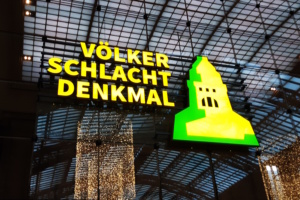 Leuchtreklame für das Völkerschlachtdenkmal im Hauptbahnhof, grün-gelbe Färbung.